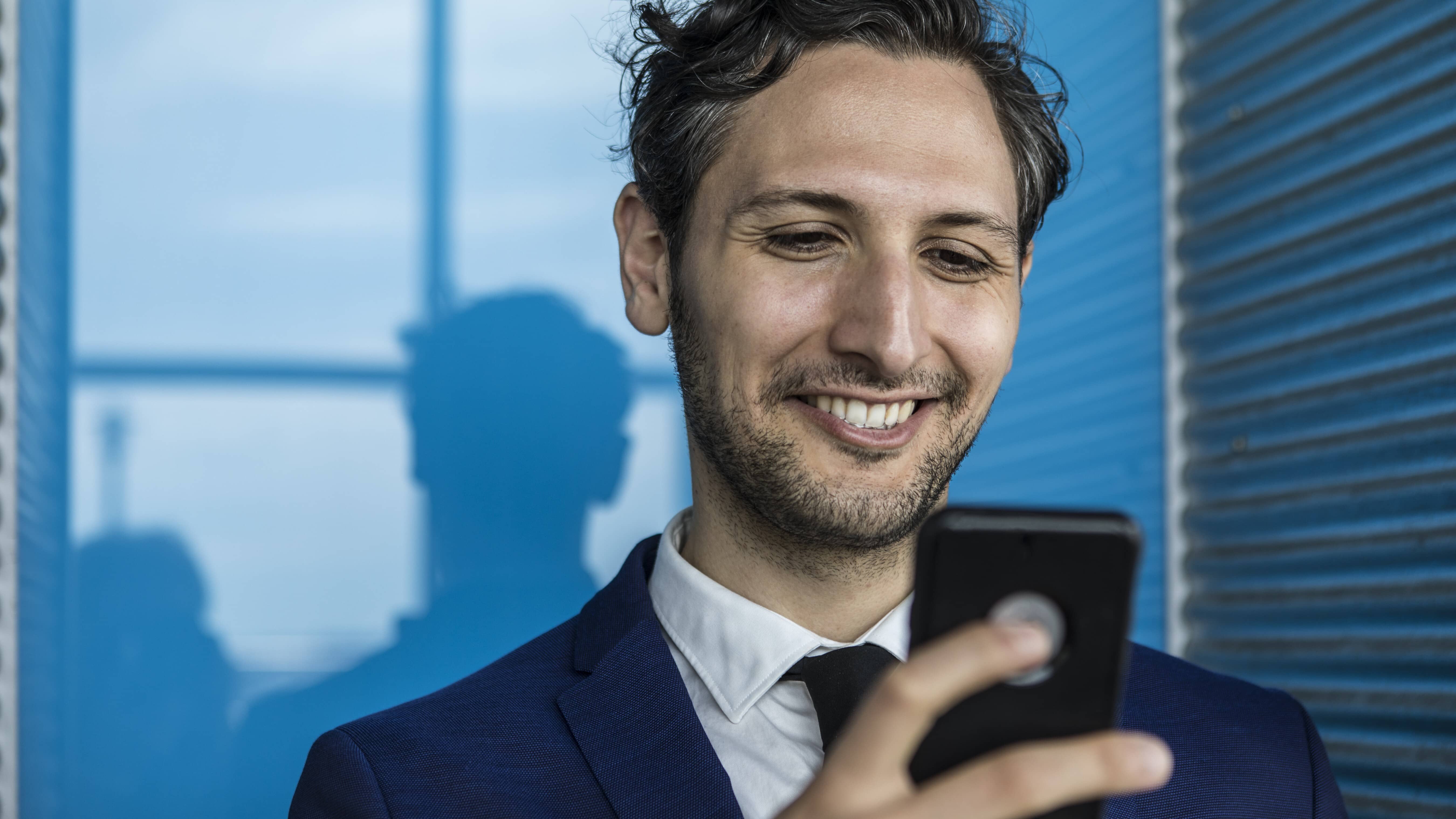 Smiling young business man holding a smartphone